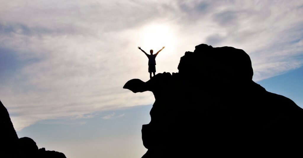 pexels photo 584179 584179 Silhouette of a person celebrating on a mountain peak against a dramatic sky, symbolizing freedom and success.